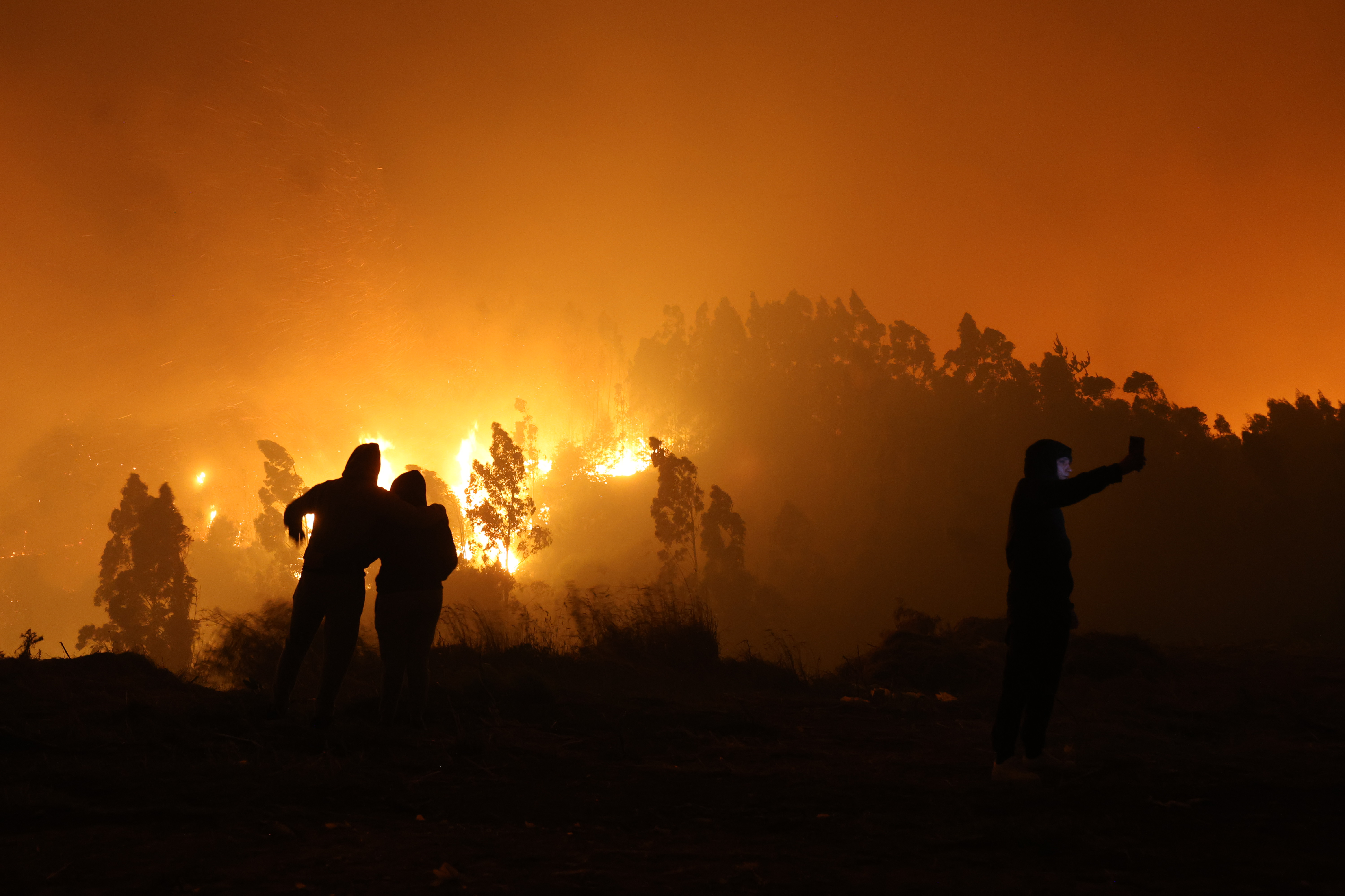 Fire advanced uncontrollably into urban areas of Penco and Lirquén driven by strong winds overnight Concepción, Chile – January 18, 2026: People watch as the flames of a wildfire advance, threat...