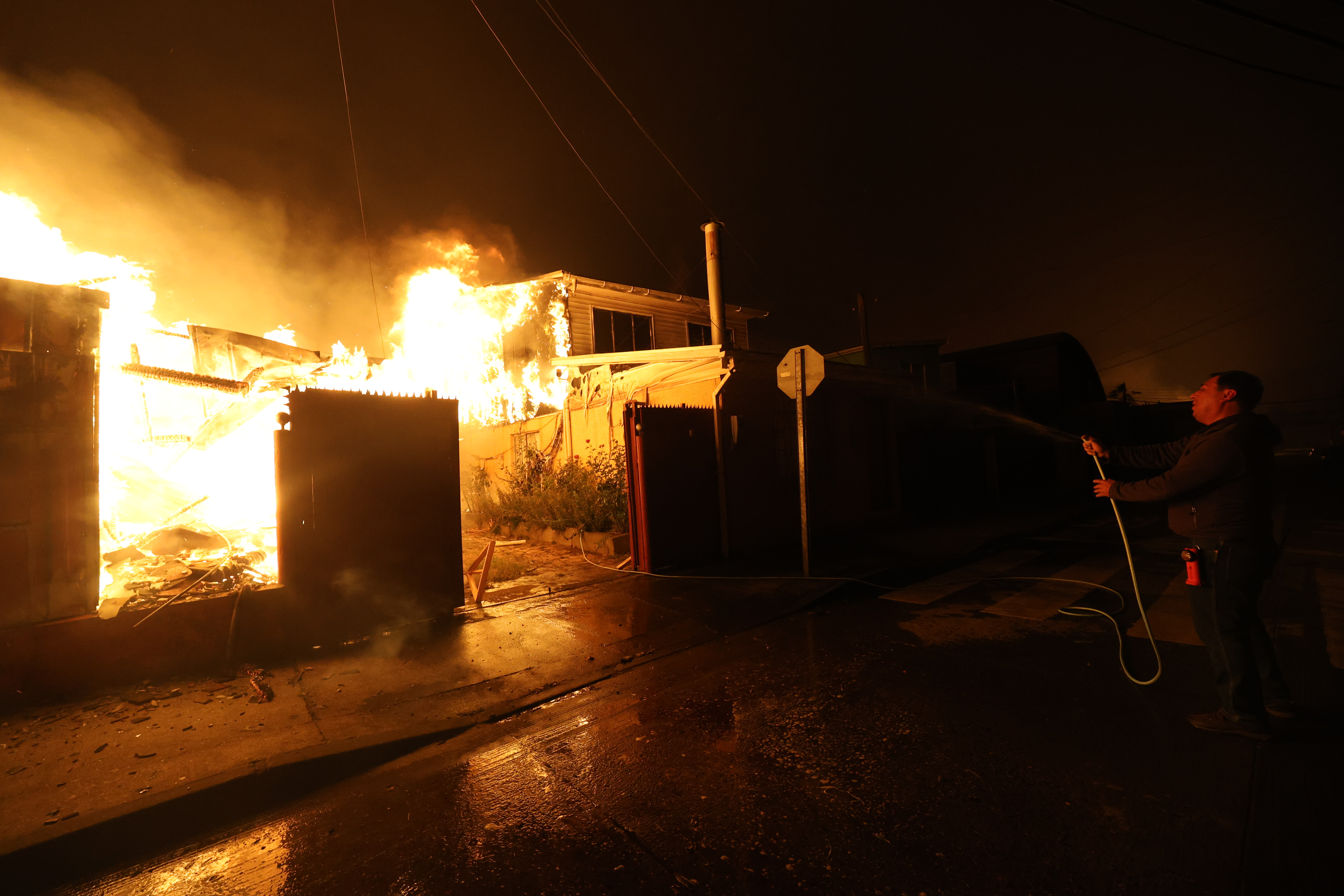 Concepción, Chile – January 18, 2026: Residents try to extinguish the fire using their own res...